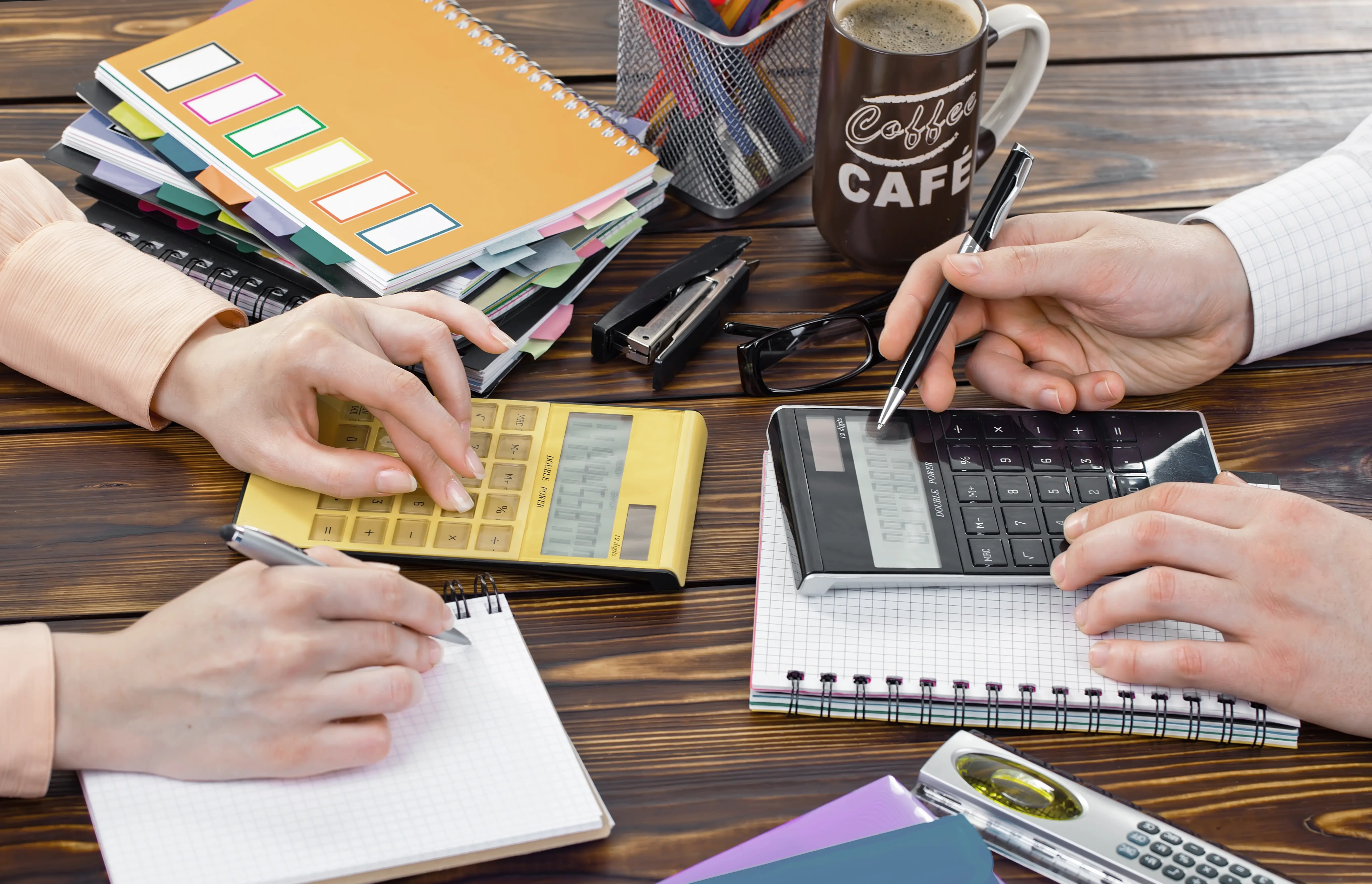 Calcul du budget d’un team building en entreprise avec calculatrices, documents financiers et analyse des coûts liés à l'événement.