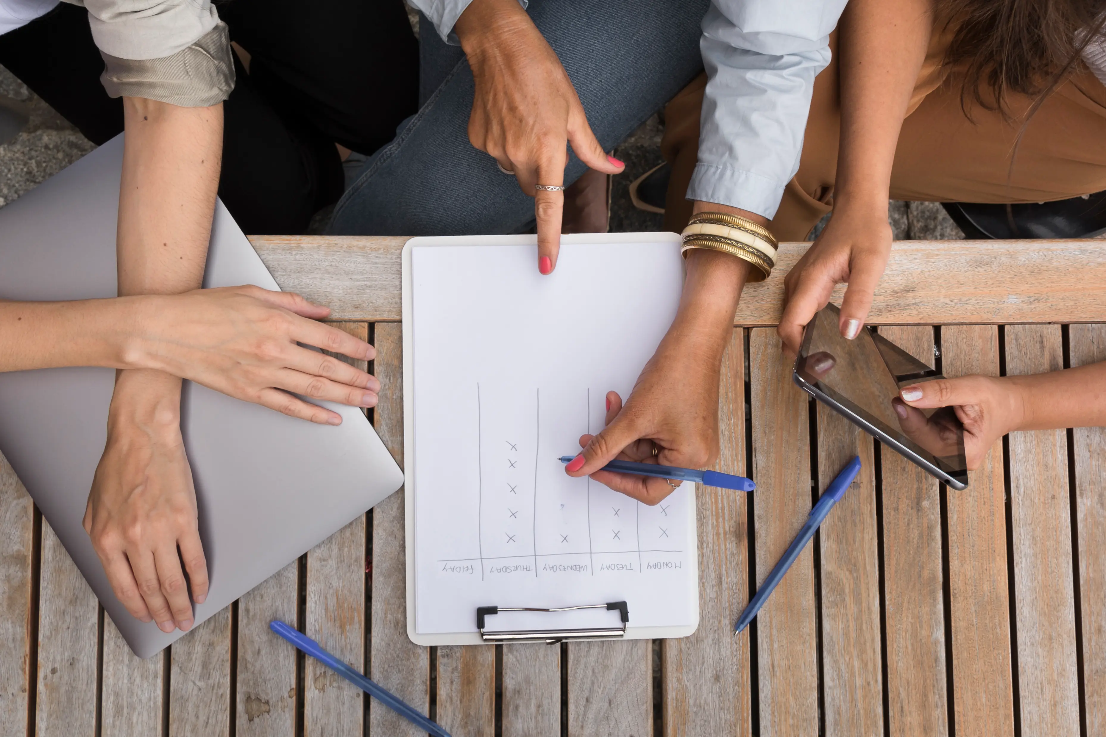 Vue de dessus de collègues planifiant un team building à l'extérieur autour d’un planning hebdomadaire — estimation du budget et organisation d'activités.